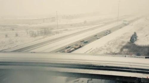 Aerial forward view over vehicles running on a highway in a snow. Daylight