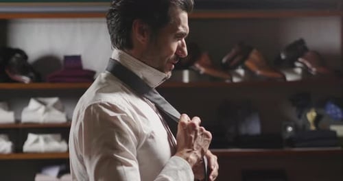 A handsome man is trying a new suit just made to measure by a tailor in a tailoring