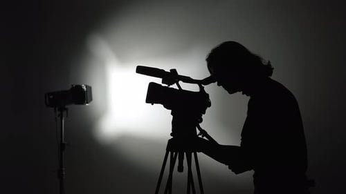Silhouette of a Cameraperson Filming with Professional Equipment