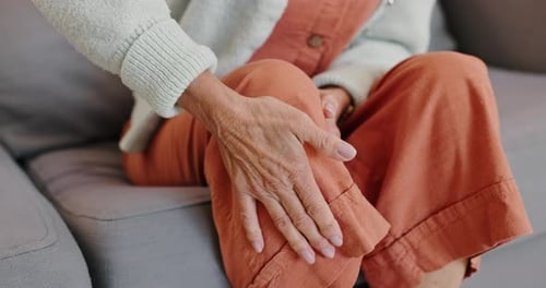 Pessoa madura, dor ou lesão no joelho na sala de estar ou no sofá para relaxar