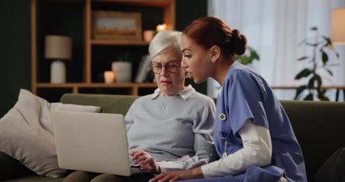 Senior woman, caregiver and laptop in home for help, support and care on sofa in living room