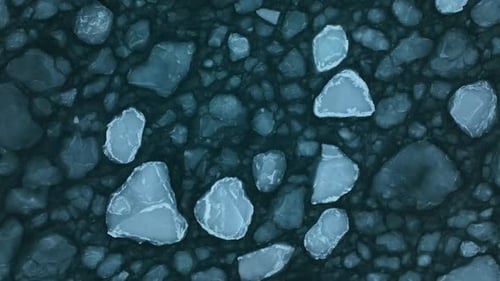Top down shot of large ice floes gently moving in the waves of the sea.