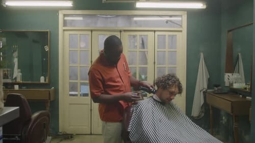 Black Barber Using Hair Clippers for Serving Male Client