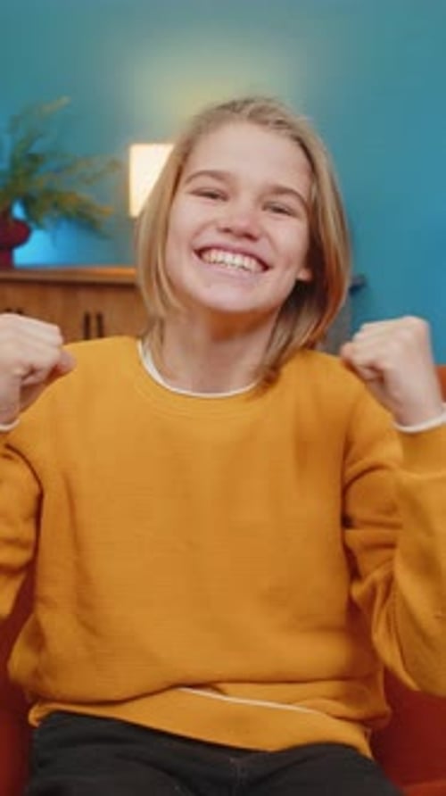 Teenager Boy Watching TV Celebrating Victory Cheering for Sports Team Sitting on Sofa at Home