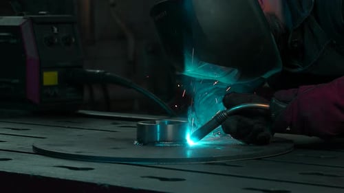 Masked worker is welding metal structures