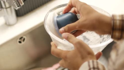 Cleaning Dishes in a Kitchen Sink with Soap and Water