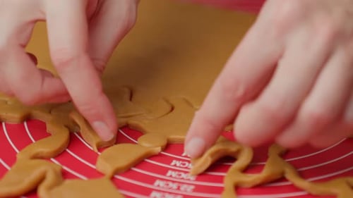Woman Cutting Christmas Cookies From Dough on Red Mat