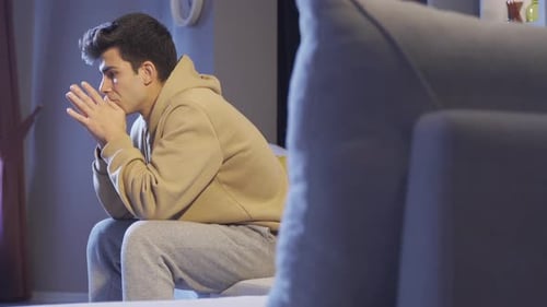 Depressed and lonely man sitting on sofa at home.