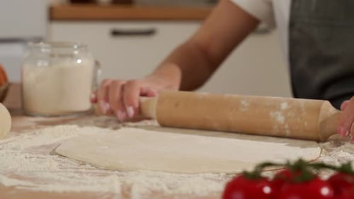 Hands of Pastry Woman Rolling Out Dough with Rolling Pin on the Table