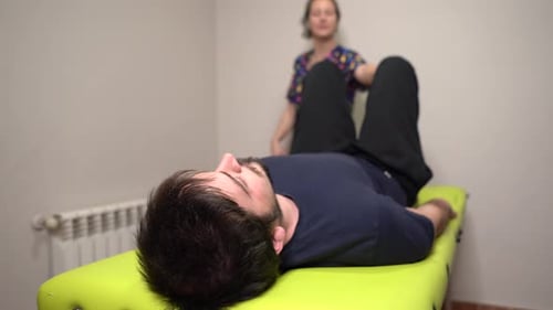 physiotherapist stretching patient on green table in clinic