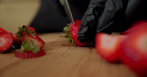 Chef in Black Gloves Slicing Fresh Strawberry on Wooden Cutting Board. Close Up