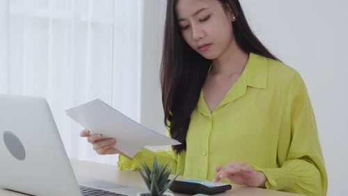 Young asian business woman using calculator with calculate tax for chart and graph report.