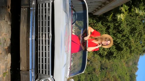 Vertical Video of Young Happy Stylish Woman in Red Dress and Hat is Standing in Vintage Car Enjoy