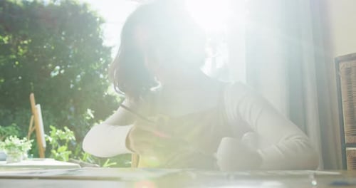 Mujer caucásica pintando en casa en un día soleado
