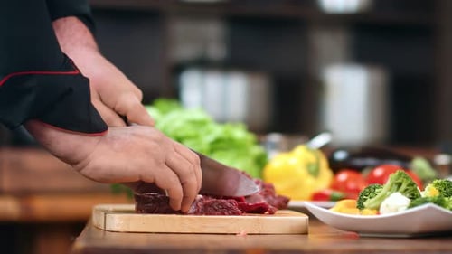 Professional Male Chef Hand Chopping Appetizing Beef on Piece