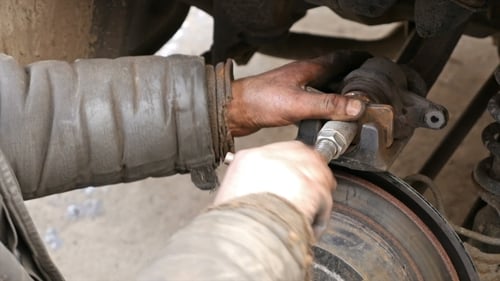 Auto Mechanic Working On Brakes In Car Repair Shop