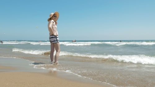 Woman Is Standing At The Beach With a Jute Hat On