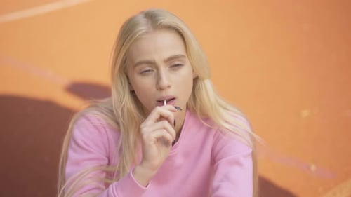 La caméra s'approche d'une jeune femme joyeuse suçant une sucette et souriant à la caméra. Portrait d'Happy