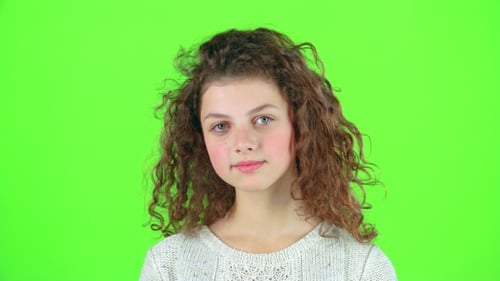 Teenage Girl Smiles and Looks Into the Distance, Covering Her Face with Her Hands. Green Screen