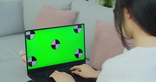 Young Asian Woman Lying on a Couch with Green Screen Laptop