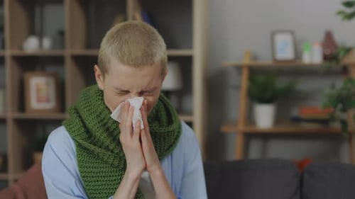 Mujer enferma sonándose la nariz en una servilleta en casa