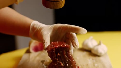 Male Tattooed Chef s Hand Seasoning Fresh Steak in a Bright Light