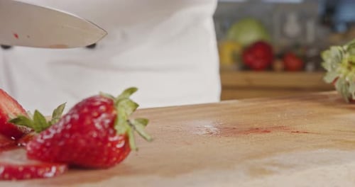 Close up of a chef knife slicing a Strawberry