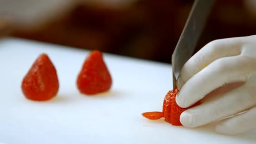 Hand with Knife Cuts Strawberry.