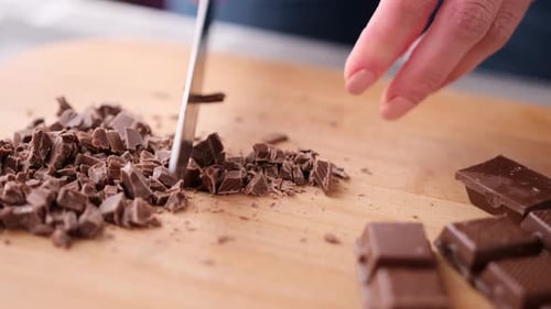Femme coupant du chocolat noir sur une planche à découper en bois