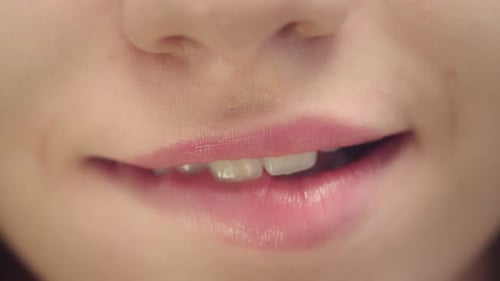 Visage féminin avec bouche souriante mordant les lèvres dodues