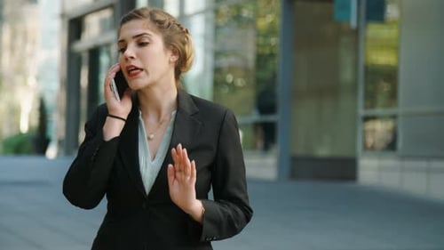 Young business woman walking on the street talking on her mobile phone