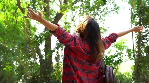 Happy young Asian woman traveler with backpack walking in forest.