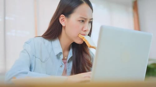 Atractiva empresaria asiática hambrienta de comer pan con la boca llena a toda prisa mientras dirige sus negocios.