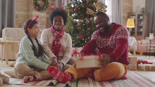 Homem negro recebendo presente de Natal de uma família amorosa