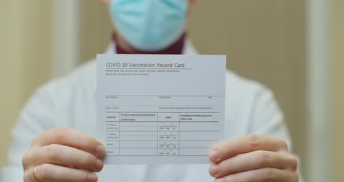 Doctor Is Holding a Vaccination Record Card and Corona Virus Vaccine Vials