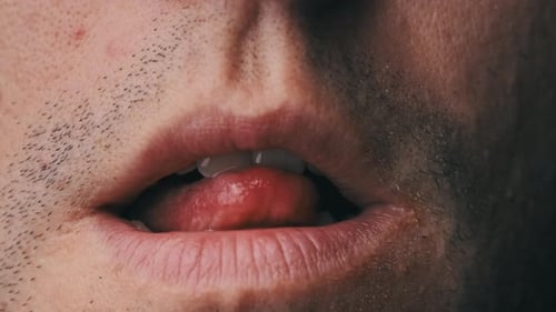 L'homme lèche érotiquement ses lèvres avec sa langue en gros plan