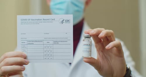 Doctor Is Holding a Vaccination Record Card and Corona Virus Vaccine Vials