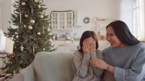 Alegre garota asiática recebendo presente de Natal da mamãe e da vovó