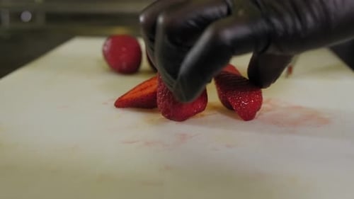 Closeup of a Chef in Black Gloves Cutting Strawberries in a Restaurant Kitchen