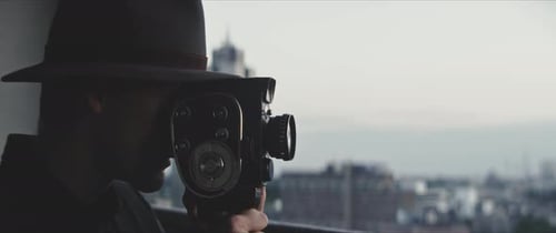 Profile of a man filming with a vintage movie camera