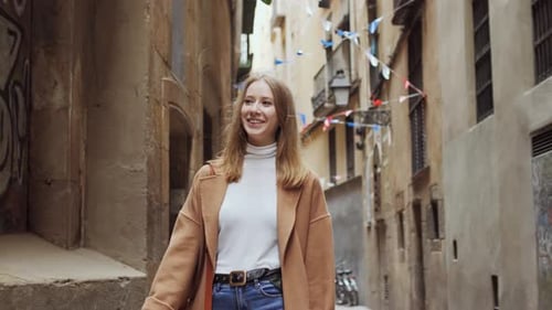 Happy Young Girl Walking with Camera Through Tight Street