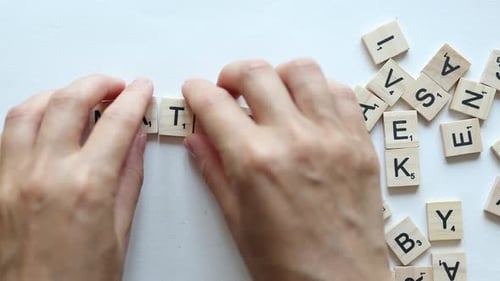 Hands Composing Word Maths From Wooden Letters on White Background