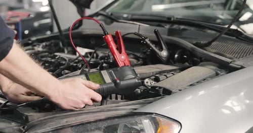 Mechanic Man Measuring Voltage On Car Battery In Auto Service. Car Servicing