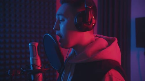 A Man in Headphones Rapping Through the Pop-filter in the Microphone - Sound Recording Studio