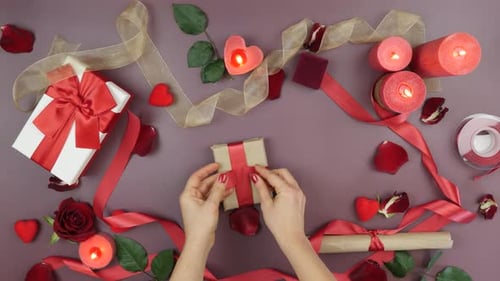 Female hands are tying red ribbon on gift box for St, Valentine's Day