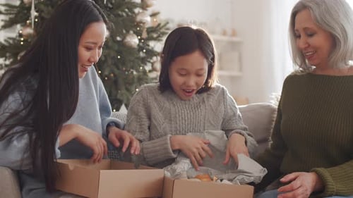Garota asiática feliz recebendo brinquedo de urso de Natal da família