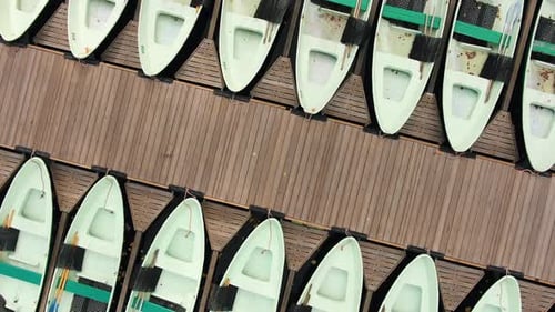 Boats Along Pier on River Strewn with Leaves in Autumn Park