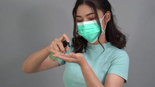 woman in a medical mask(surgical mask) using alcohol gel, coronavirus protection