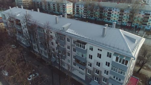 Apartment Building with Sloppy Roof and Bare Trees in Winter