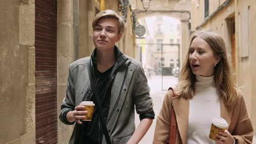 Two Stylish Friend with Cap of Coffee Talking During Walk at the Street
